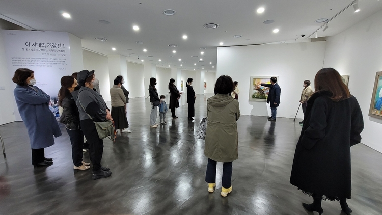  전시장을 찾은 손님들에게 작품 설명을 하고 있다. 
