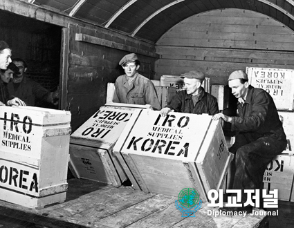  대한민국 재건<br>
독일 철도 노동자들이 UN의 특별기구인 국제 피난민기구(IRO)가 한국에 보내기 위해 기표를 한 적화물 앞에 있는 장면. 4명의 IRO 간부가 UN의 민간 피난민을 돕기 위한 임무를 수행하기 위해 한국에 도착했다.<br>
<br>
FOR THE PEACEFUL REBUILDING OF KOREA<br>
Railroad workers in Germany are shown here loading supplies earmarked for Korea by the International Refugee Organization (IRO), a U.N. Specialized Agency. Four IRO welfare officers are already in Korea with the U.N. Mission aiding civilian refugees.