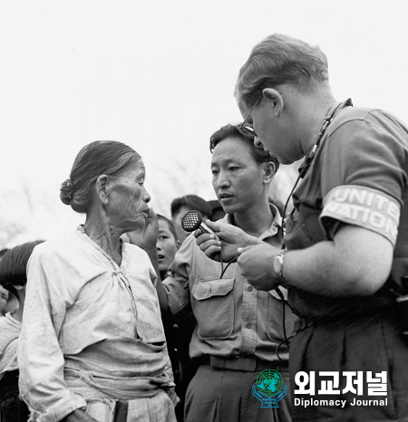  한국전쟁<br>
우측에 있는 UN 신문기자인 죠지모헌이 UNCOK 통역관인 헨리박씨의 통역으로 김해근처 난민캠프로 가고 있는 피난민들과 인터뷰를 하고 있다.<br>
인터뷰 내용은 전 세계에 방영키 위해 UN 방송국에서 인터부한 다.<br>
대한민국, 1950년 9월<br>
<br>
THE WAR IN KOREA<br>
Mr. GEORGE MOSSHON, right, U.N. Press Officer. Records interviews with refugees heading for the camp near Kimhae, with the help of Mr. HENRY PARK. UNCOK Interpreter. The records will be programs to be broadcast all over the world.<br>
South Korea, September 1950