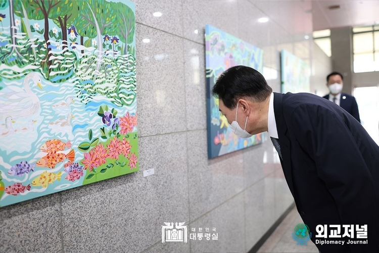  윤석열 대통령은 2022년 7월 25일 출근길에 약식 기자회견(도어스테핑)을 마친 뒤 로비에 새로 걸린 이다래 작가의 "백조의 호수" 그림을 둘러보고 있다. 이날 1층 양옆 벽면에는 발달 장애 작가들의 작품 7점이 처음 전시됐다. (사진=대통령실)