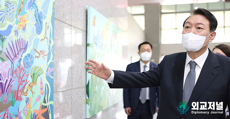 President Yoon Suk-yeol looks at the newly hung painting "Woodcarver's Adventure (Sea)" by Artist Lee Da-rae in the lobby after a brief press conference<br>
(doorstepping) on his way to work on July 25, 2022. On this day, seven works by artists with developmental disabilities were displayed for the first time on the<br>
walls on both sides of the first floor.