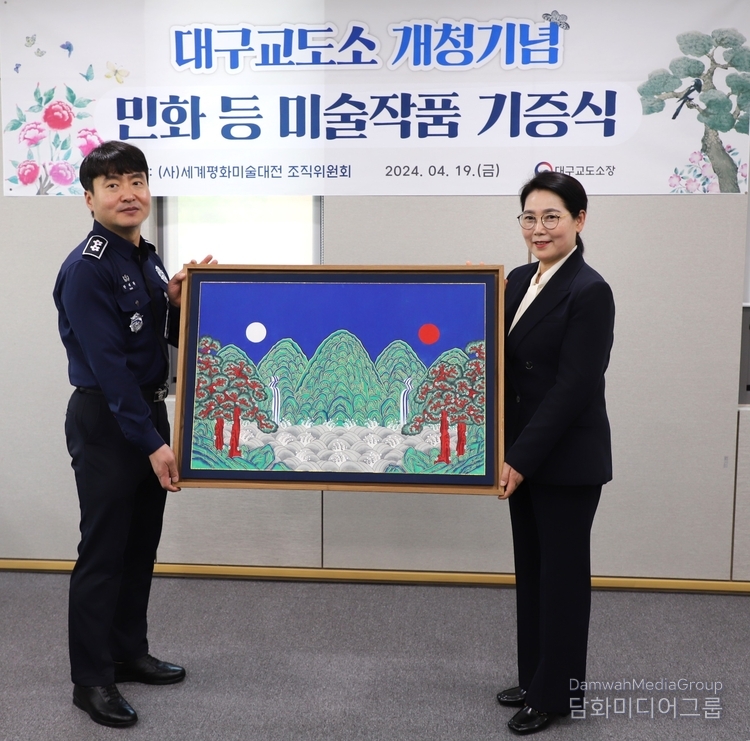 한태환 대구교도소장에게 이미형 명지대 문화콘텐즈 · K-민화 주임교수가 작품을 기증하고 있다. 