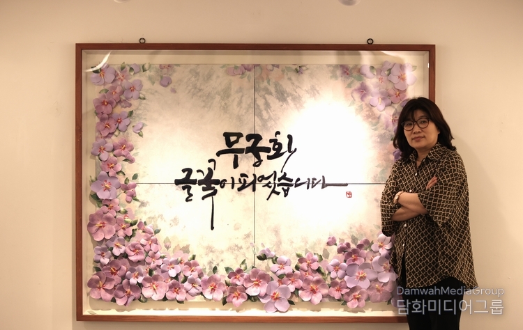 전은숙 작가가 자신의 작품 무궁화 꽃이 피었습니다. 앞에서 포즈를 취하고 있다. 