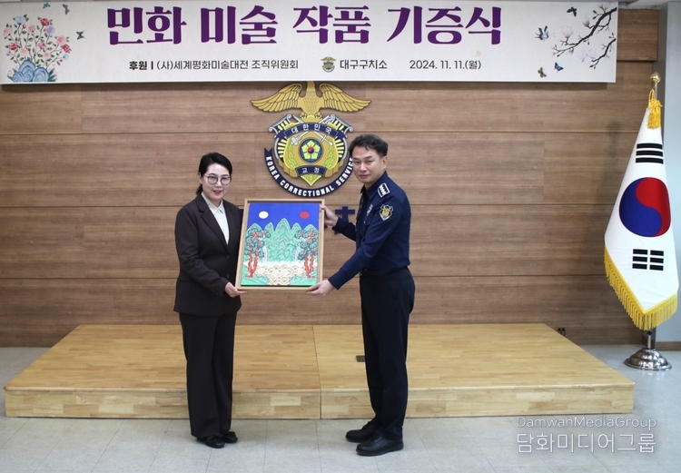 사단법인 세계평화미술대전 조직위원회 민화분과 위원장 이미형(명지대 교수)가 대구 구치소 김영광 소장에게 작품을 기증하고 있다.