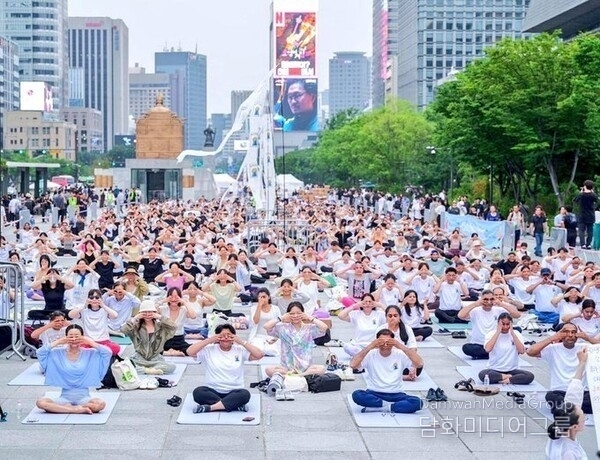  광화문 광장에 모인 수백 명의 참가자들이 함께 요가를 수련하고 있다.