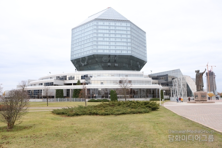 벨라루스 민스크의 상징적 건축물인 국립도서관(National Library of Belarus) 앞에서 한국 대표단이 기념촬영을 하고 있다. 팔각형 다이아몬드 형태의 독창적인 외관은 ‘지식의 보석’을 상징하며, 밤이 되면 건물 전체에 LED 조명이 켜져 붉고 푸른 빛으로 환하게 빛나 도시의 랜드마크로 변신한다. 지성의 상징이자 예술적 건축미를 겸비한 이곳은 민스크 시민들이 가장 자랑스러워하는 문화공간이다.( 사진-최동호 국장)